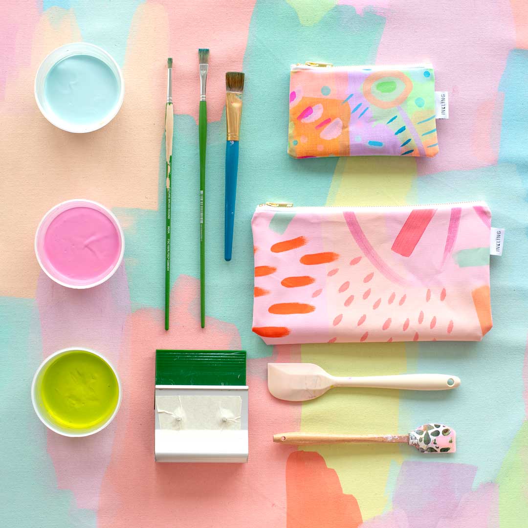 brushes, pastel paints, tools and bags on a brightly coloured background